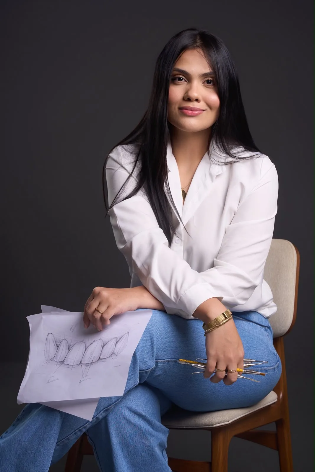 Karen Brandão sentada, com o desenho de um sorriso e instrumentos odontológicos
