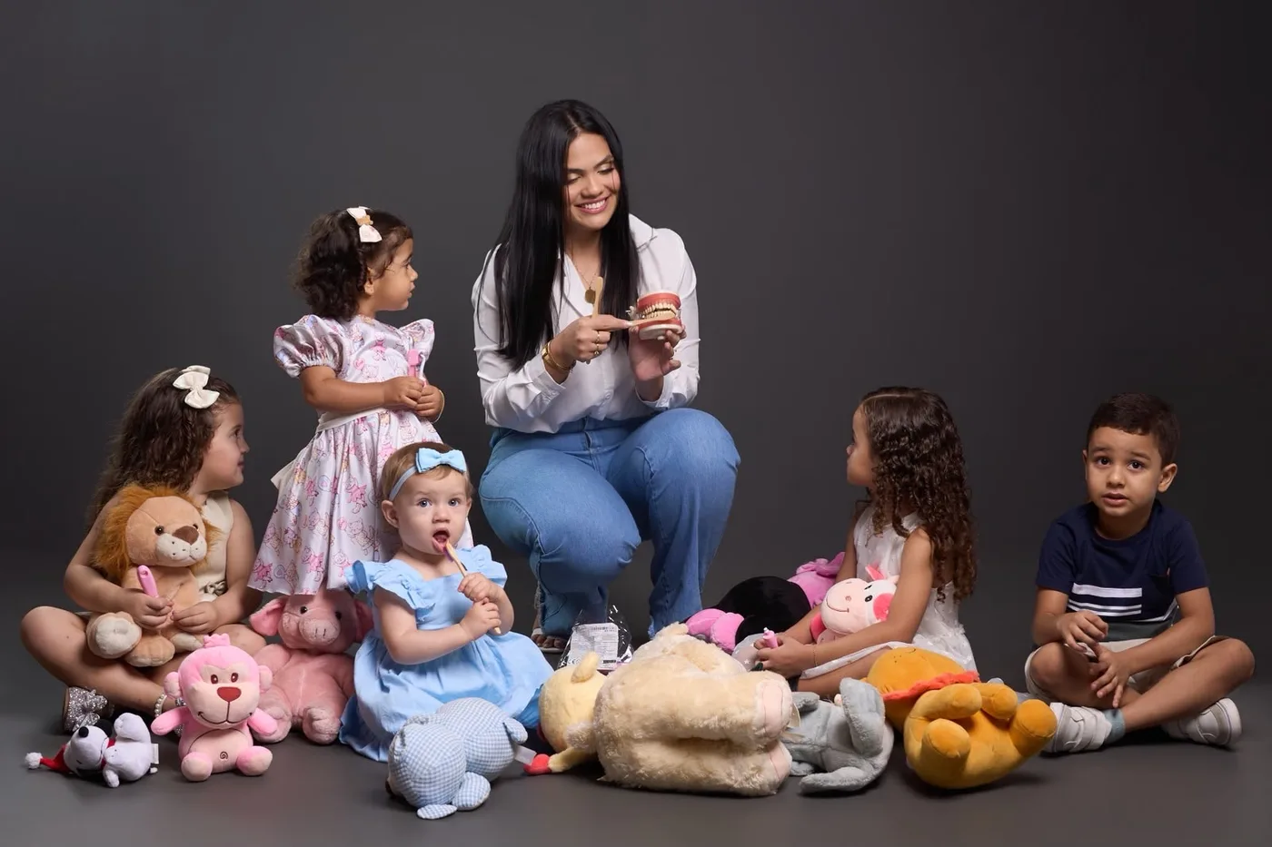 Karen Brandão com crianças, mostrando a escovação em um modelo