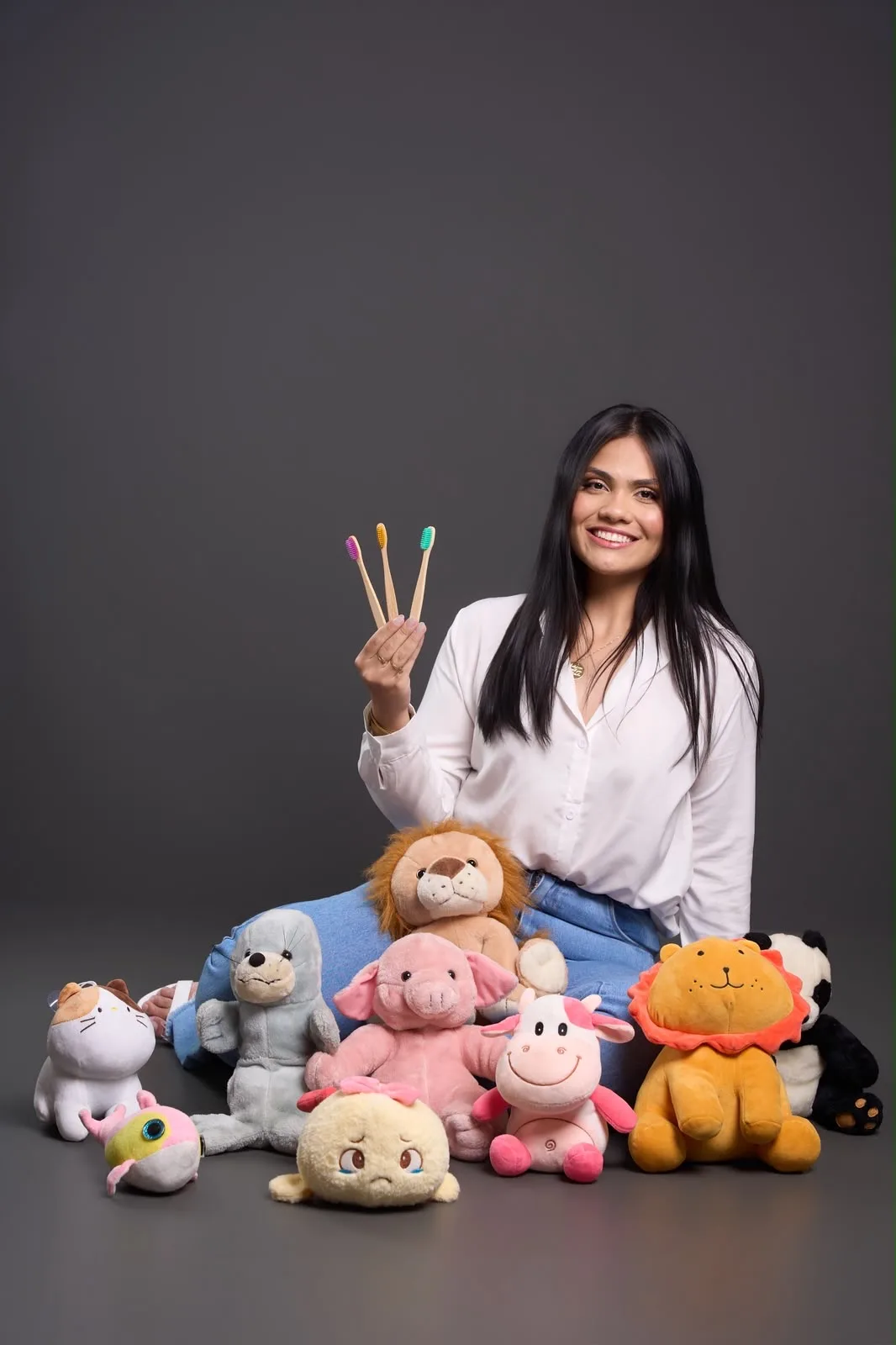Karen Brandão sorrindo com escovas de dentes de bambu e bichinhos de pelúcia